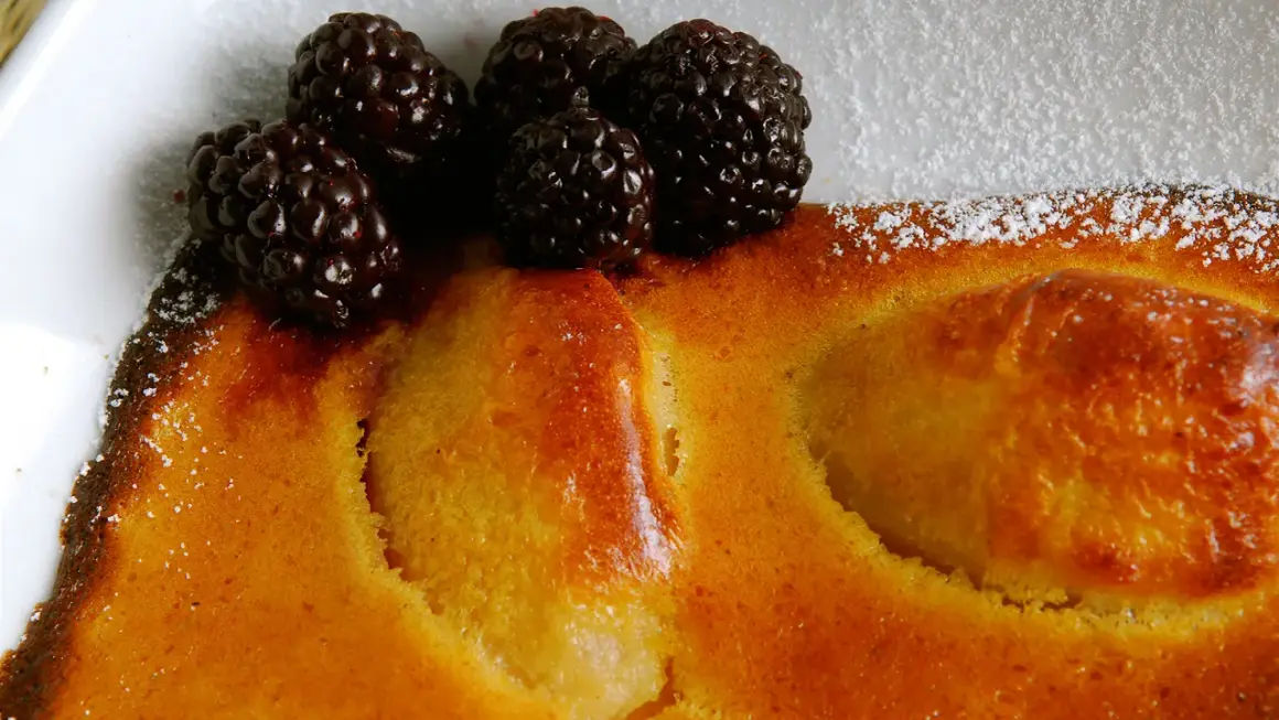 Delicioso postre de peras al horno, cubierto con moras frescas y espolvoreado con azúcar glas.
