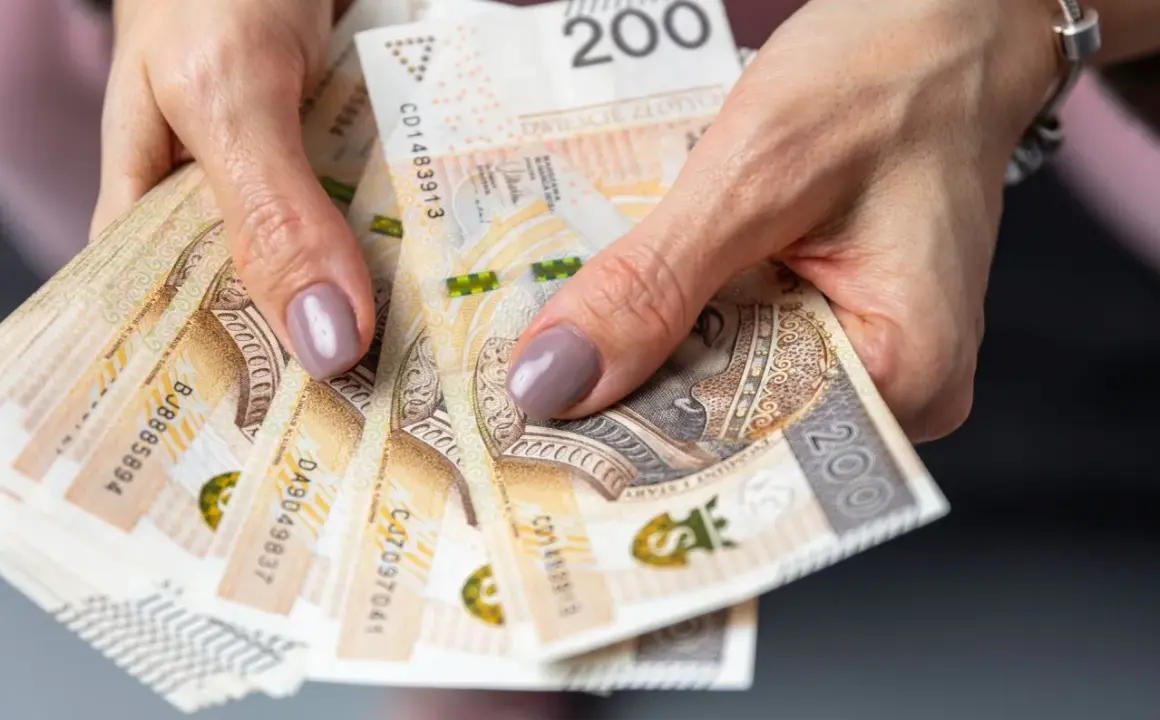Dłonie trzymające stos banknotów 200 zł. Pieniądze mogą symbolizować oszczędności na przyszłość, np. na okresową emeryturę kapitałową.