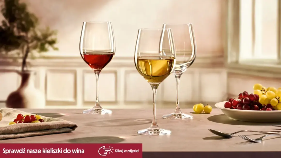 Eleganckie kieliszki do wina, jeden z czerwonym winem, drugi z białym, gotowe na degustacje. Obok winogrona i sztućce.