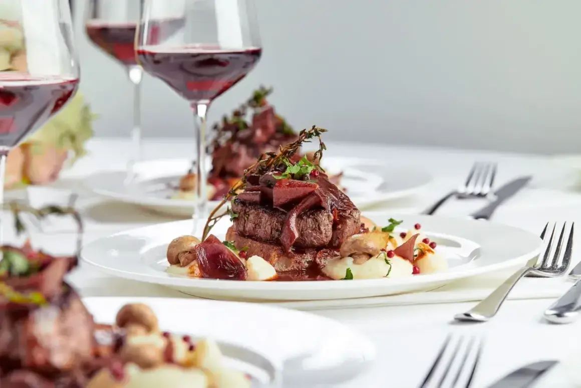 Eleganckie danie z wołowiny z puree i grzybami, podane z czerwonym winem. Zastanawiasz się, ile za talerzyk na wesele?