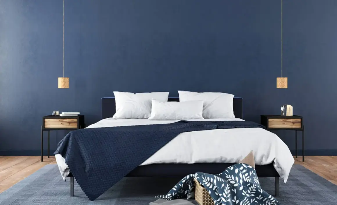 Ein modernes Schlafzimmer mit tiefblauen Wänden, die Ruhe und Harmonie ausstrahlen – eine ideale feng shui schlafzimmer farbe. Weiße Bettwäsche und dunkle Akzente schaffen ein stilvolles Ambiente.