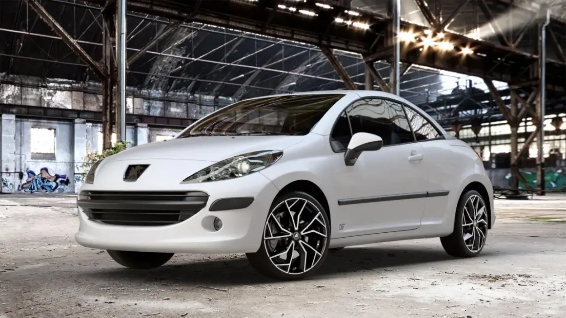 Vit Peugeot 207 cabriolet med snygga fälgar i en övergiven lagerlokal. Inga problem här, bara stil!