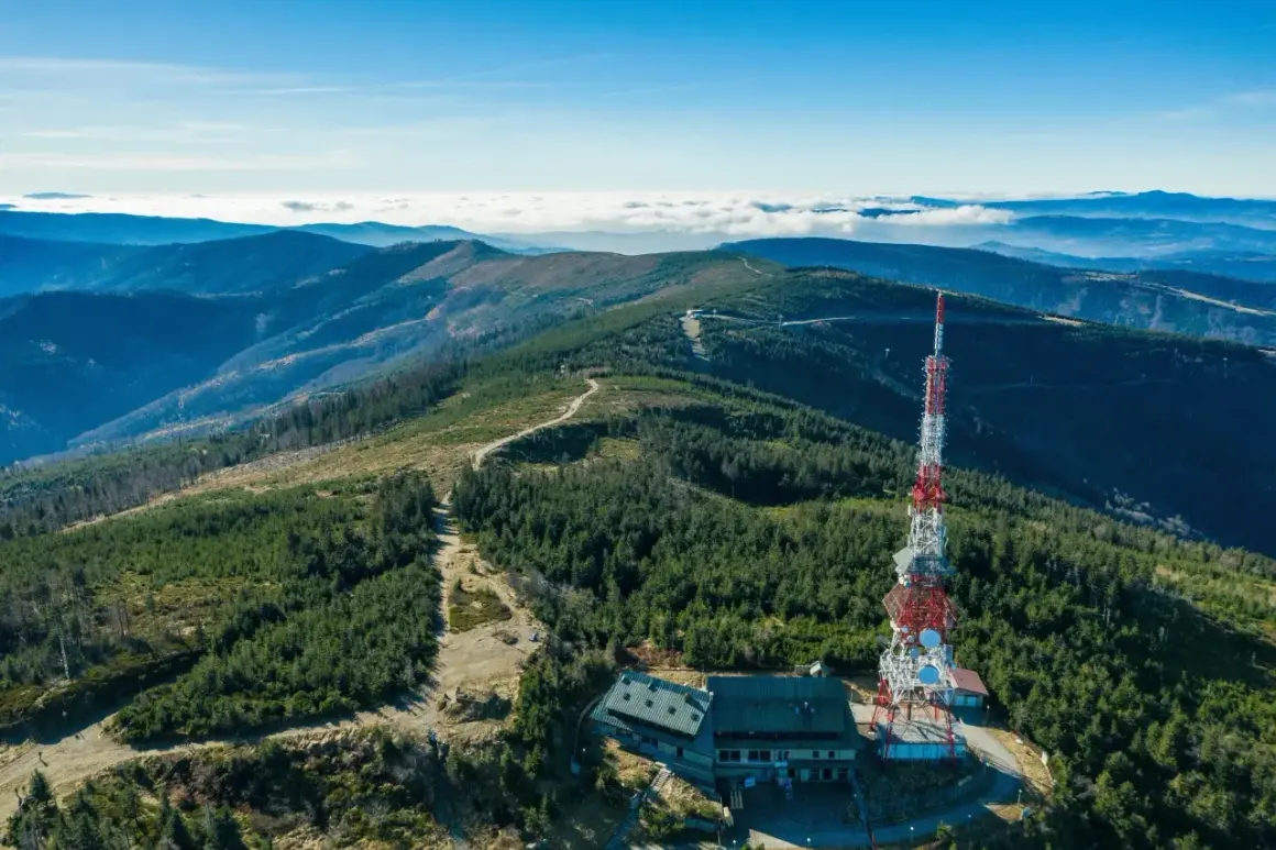 Widok na szczyrk jakie góry, z wieżą telekomunikacyjną i schroniskiem na tle pasm górskich i morza chmur.