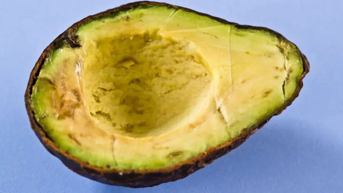 Halbierte Avocado auf blauem Hintergrund. Die Avocado-Wirkung auf die Haut ist bekannt, sie ist reich an Vitaminen und gesunden Fetten.