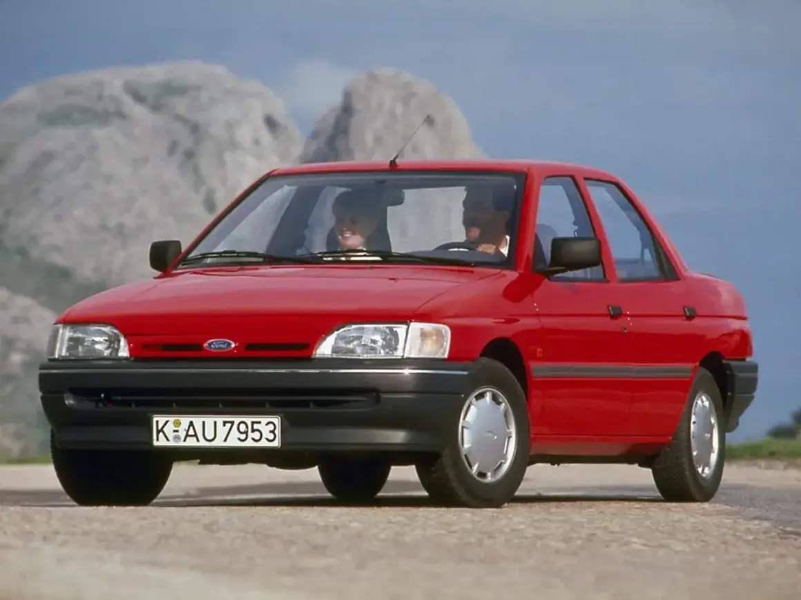 Czerwony Ford Orion z parą uśmiechniętych ludzi w środku, jadący po górskiej drodze.