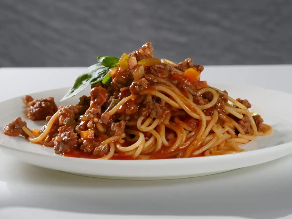 Ein Teller Spaghetti Bolognese, liebevoll zubereitet, mit frischem Basilikum garniert. Perfekt, um bolognese selber machen zu lernen.