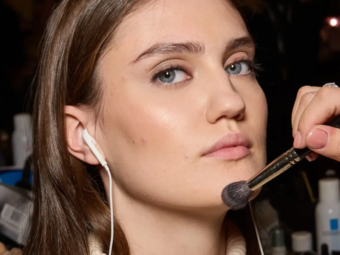 Applicazione di un pennello per il trucco sul viso, forse per schiarire il fondotinta o sfumare il blush.