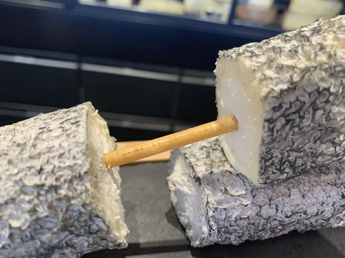 Deux morceaux de fromage de chèvre, un "tête de maure", sont reliés par un bâtonnet en bois.