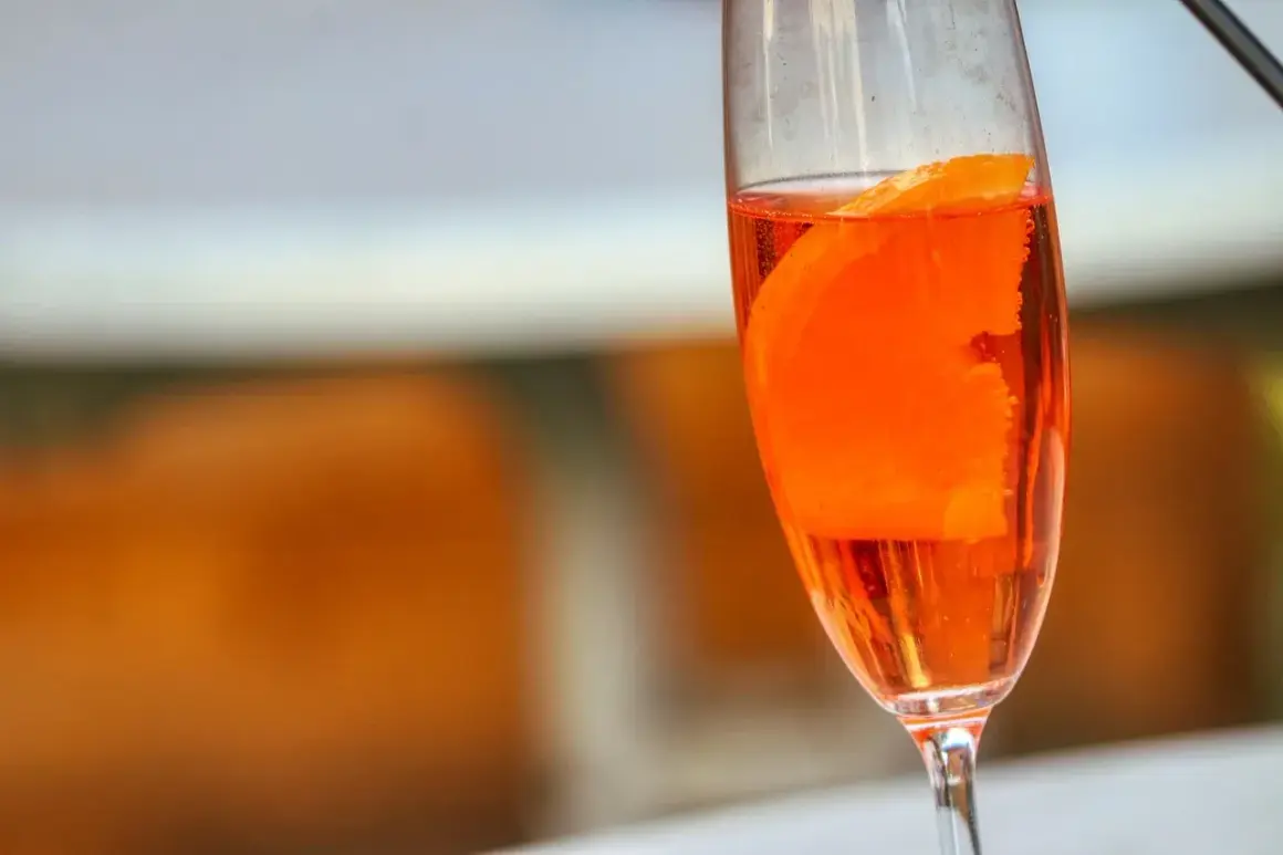 Orzeźwiający lillet drink z plasterkiem pomarańczy w kieliszku, gotowy na letnie popołudnie.