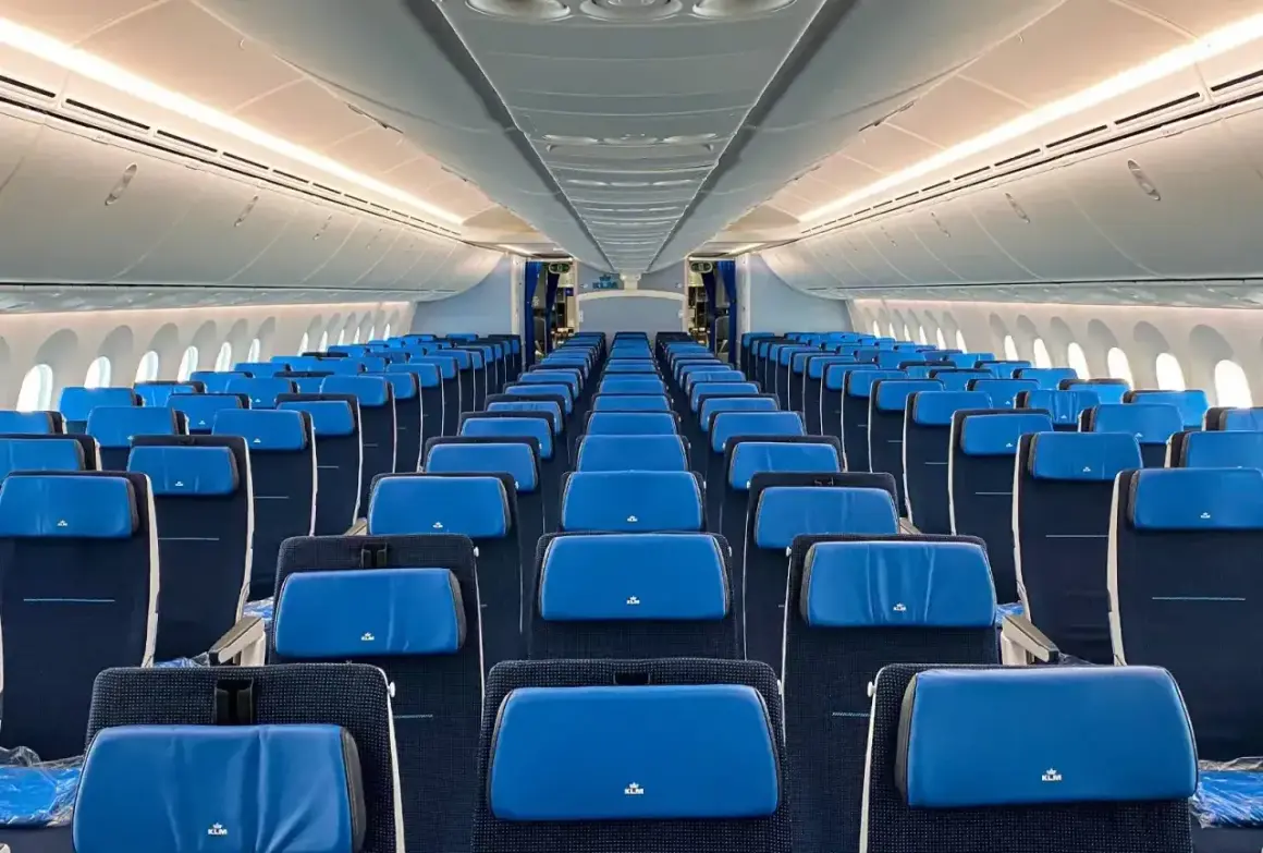 Puste rzędy siedzeń w kabinie samolotu Boeing 787-9. Błękitne zagłówki z logo KLM.