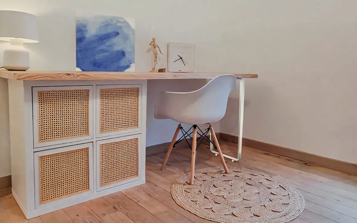 Bureau en pin relooké avec des portes en rotin. Une chaise blanche et un tapis rond complètent ce coin bureau moderne.