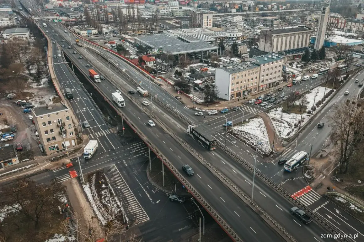 Widok z lotu ptaka na estakadę Kwiatkowskiego z ruchem samochodowym, budynkami i terenami zielonymi.