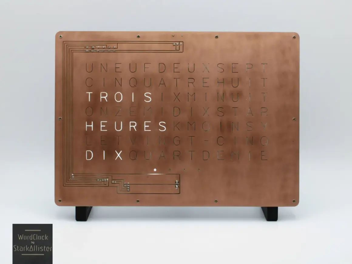 Horloge murale au design industriel, avec une plaque de cuivre gravée de lettres formant des mots. Une lettre métal unique pour un style épuré.
