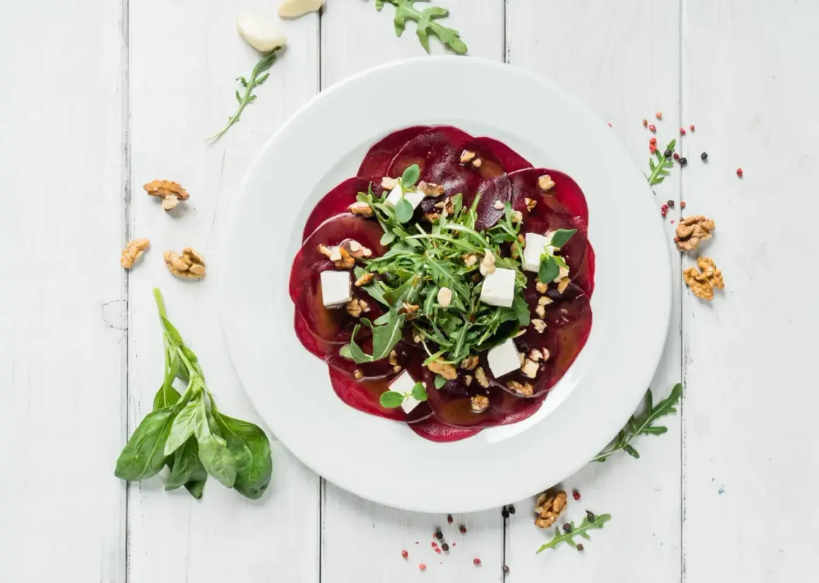 Eleganckie carpaccio z buraka z fetą, orzechami i rukolą. Idealny przepis na lekki i zdrowy posiłek.