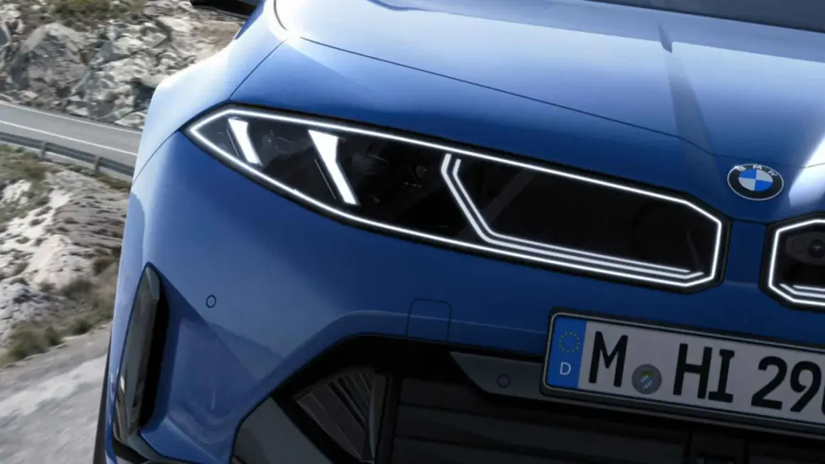 El frontal de un BMW azul eléctrico con tracción trasera, listo para devorar curvas en una carretera de montaña.