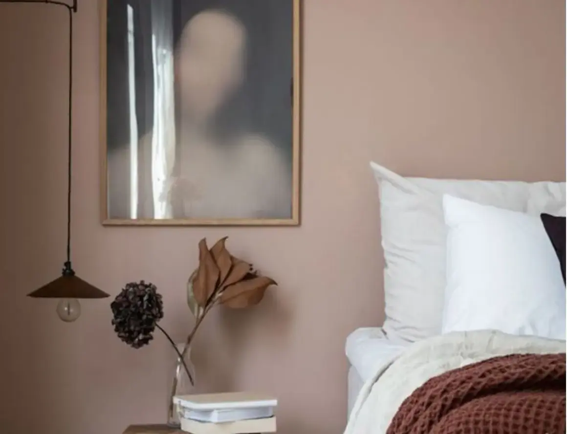 Un angolo letto con pareti color malva, un quadro astratto e un vaso con fiori secchi. Gli abbinamenti verde malva colore creano un'atmosfera rilassante.