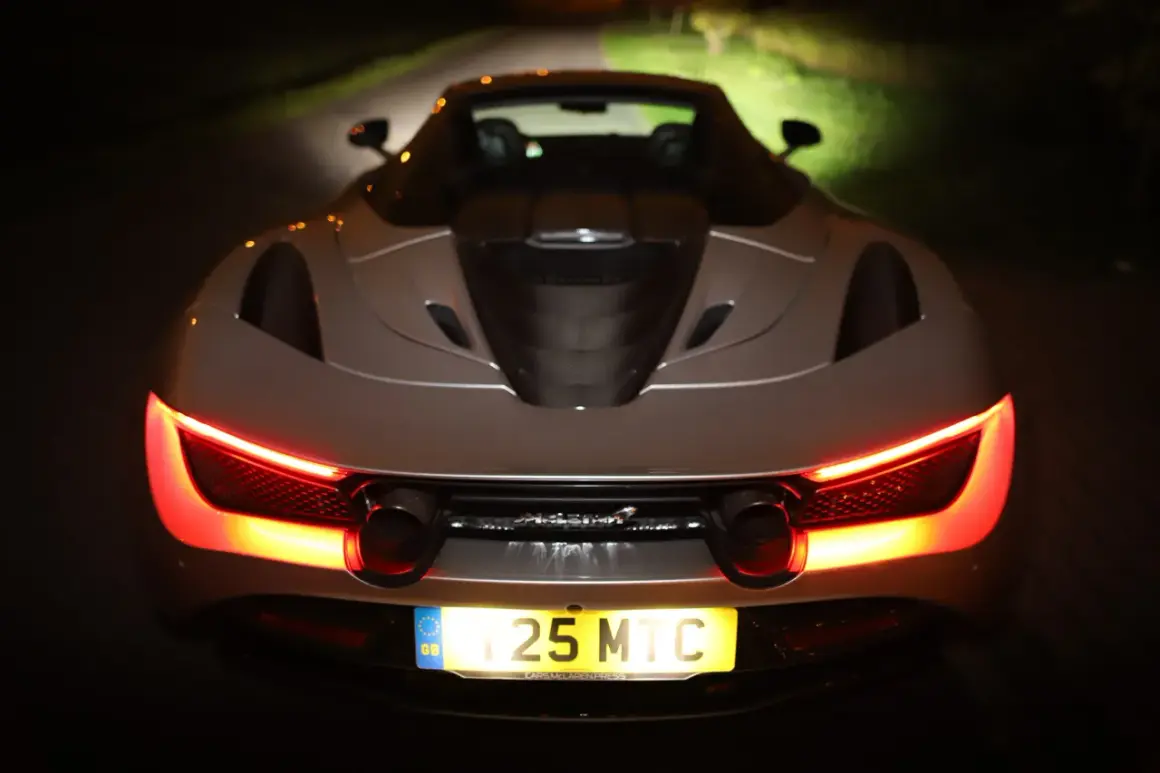 Tył srebrnego McLarena 720S nocą, z włączonymi czerwonymi światłami. Zastanawiasz się nad mclaren 720s cena?