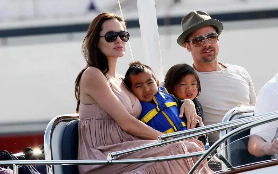 Angelina Jolie med sina barn på en båt. En av barnen bär en blå flytväst.