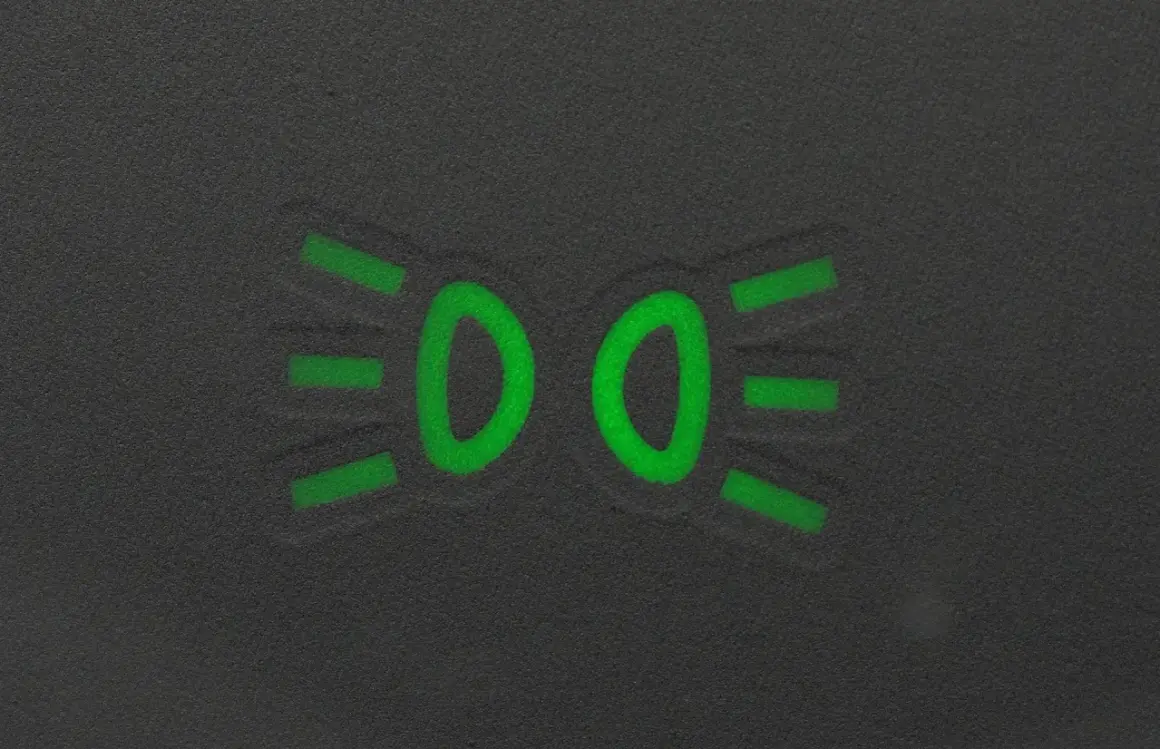 Zielony symbol świateł mijania na ciemnym tle.