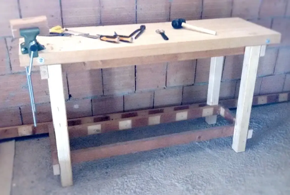 Un banco da lavoro in legno, pronto per iniziare a fare un tavolo in legno. Attrezzi come morsa, martello e pinze sono pronti all'uso.