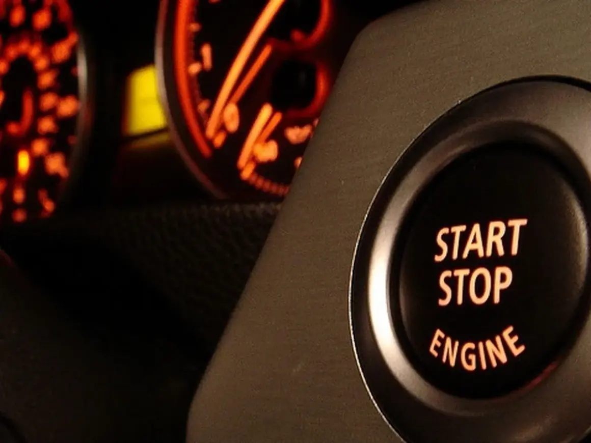 Bouton "START STOP ENGINE" illuminé, prêt à démarrer ou arrêter le moteur. Les cadrans du tableau de bord brillent en orange.
