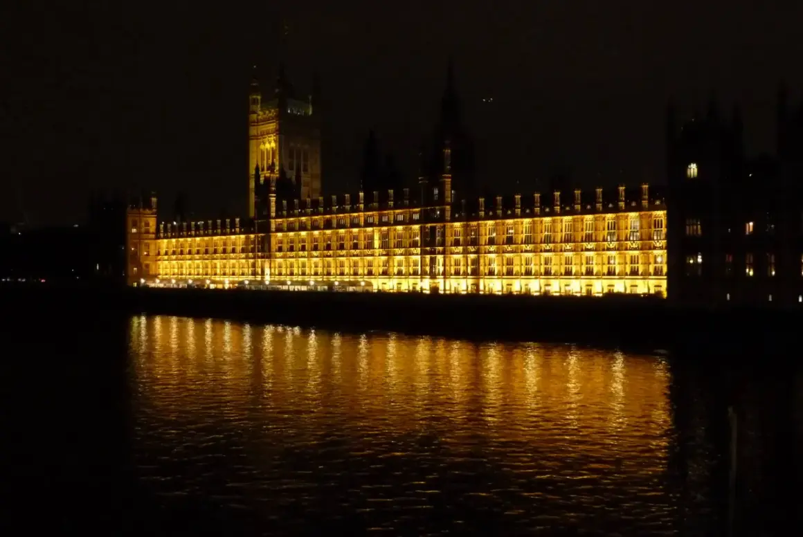 Palazzo di Westminster illuminato, un'icona di Londra by night, con riflessi dorati sull'acqua scura del Tamigi.