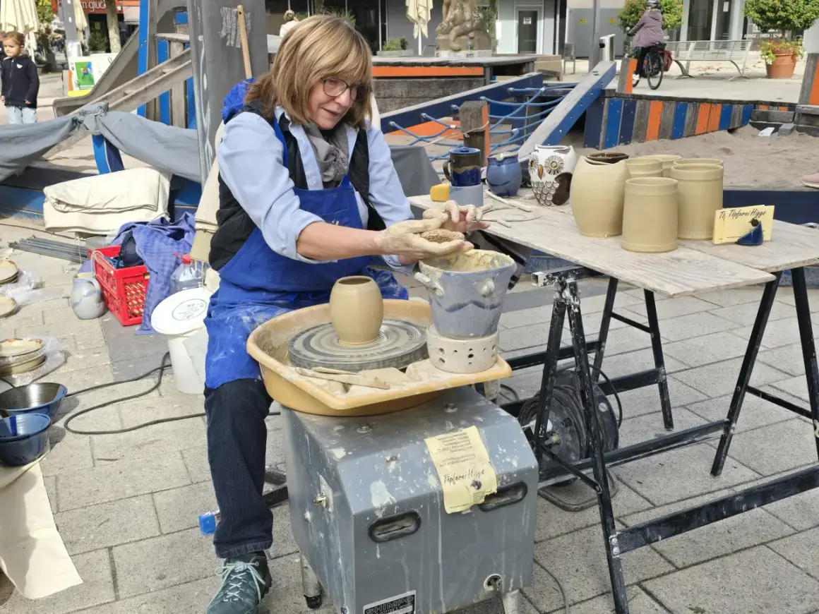 Töpferin am Werk am Hafenmarkt Heilbronn. Sie formt mit geübten Händen Ton auf ihrer Töpferscheibe.