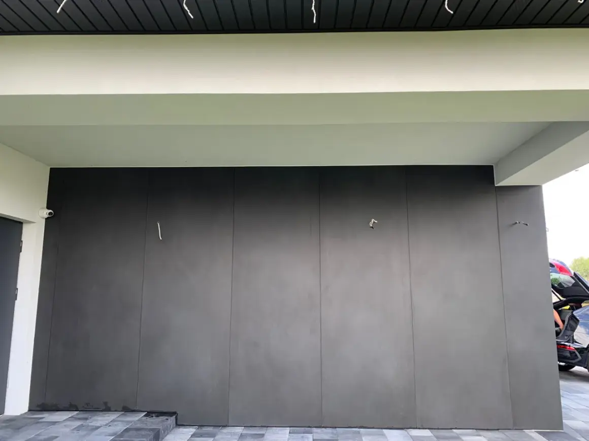 Nowoczesna elewacja z płyt spieku kwarcowego w ciemnoszarym kolorze, tworząca minimalistyczną i elegancką fasadę.