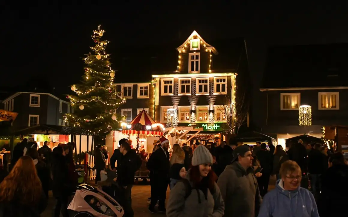 Menschen genießen den stimmungsvollen Radevormwald Weihnachtsmarkt mit beleuchtetem Baum und festlich geschmückten Häusern.