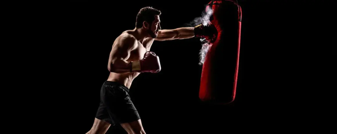 Boxer training to strengthen his chin for boxing, punching a red heavy bag with force.