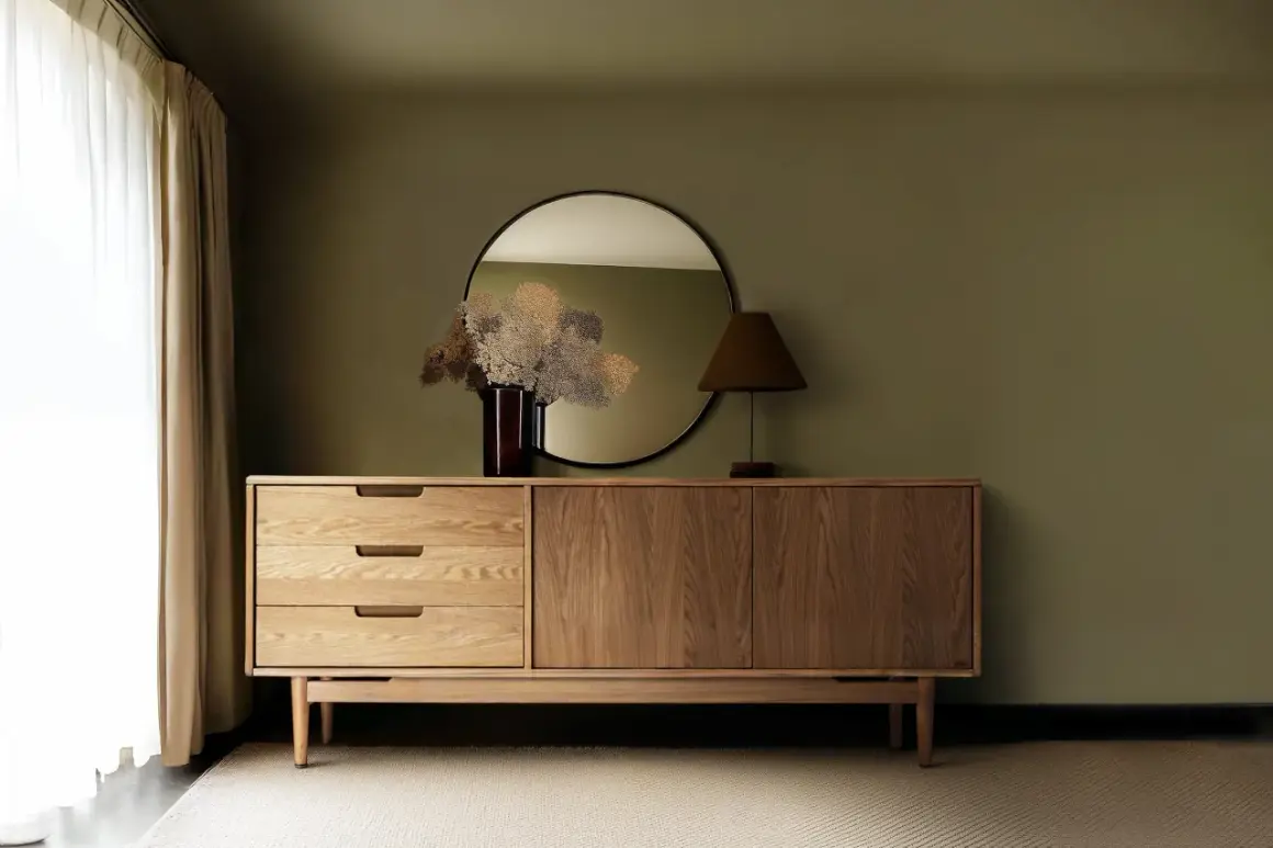 Ein Sideboard aus Holz mit Schubladen und Türen, darüber ein Spiegel und eine Lampe. So sieht ein praktisches Sideboard aus.
