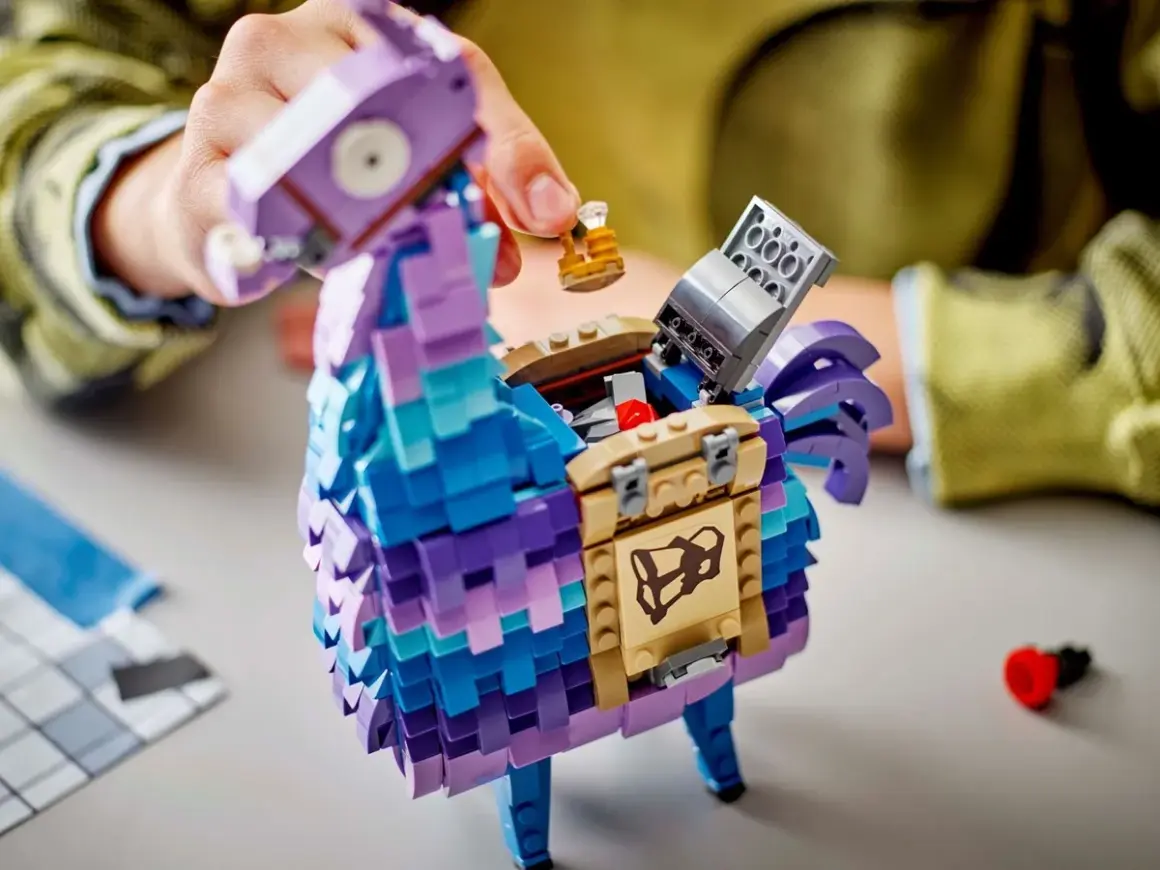 Ręce składają kolorową, klockową **lamę z Fortnite**. Otwiera się jej brzuch, odsłaniając skarb.