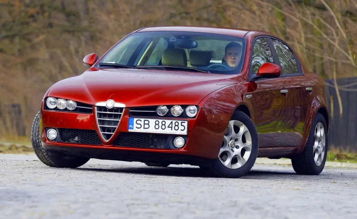 Czerwone Alfa Romeo 159 z kierowcą. Zastanawiasz się, jaki silnik ma to Alfa Romeo 159?