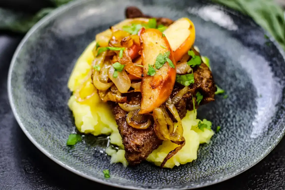 Leber Berliner Art auf Kartoffelpüree mit karamellisierten Zwiebeln und Apfelscheiben, garniert mit Petersilie.