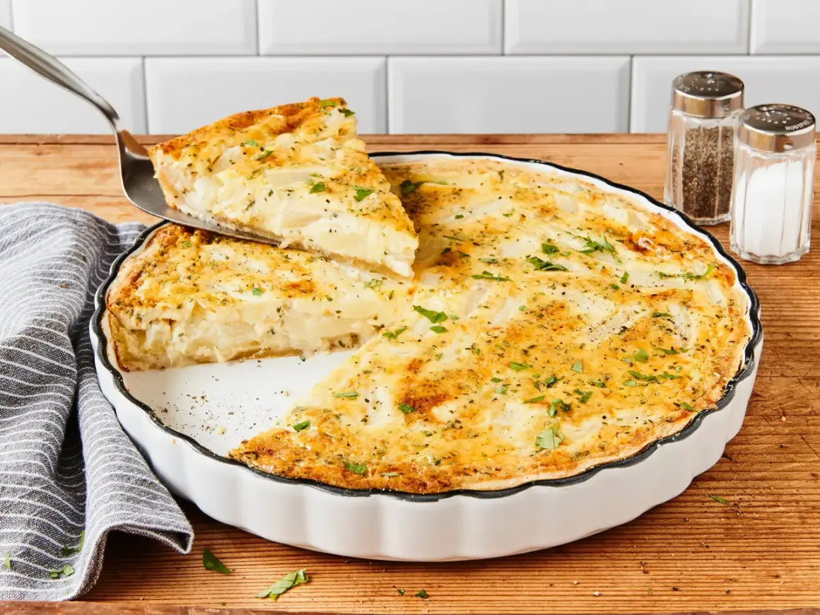 Eine köstliche Spargel Quiche wird serviert. Ein Stück wird mit einem Tortenheber herausgehoben, garniert mit frischer Petersilie.
