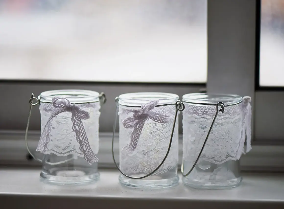 Drei hübsch gestaltete Windlichter aus Glas mit zarter Spitze und Schleifen.