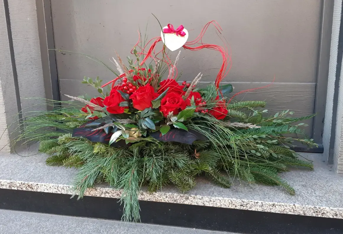 Wiązanki z róż na Wszystkich Świętych, ozdobione sercem i gałązkami iglaków, tworzą elegancką kompozycję.