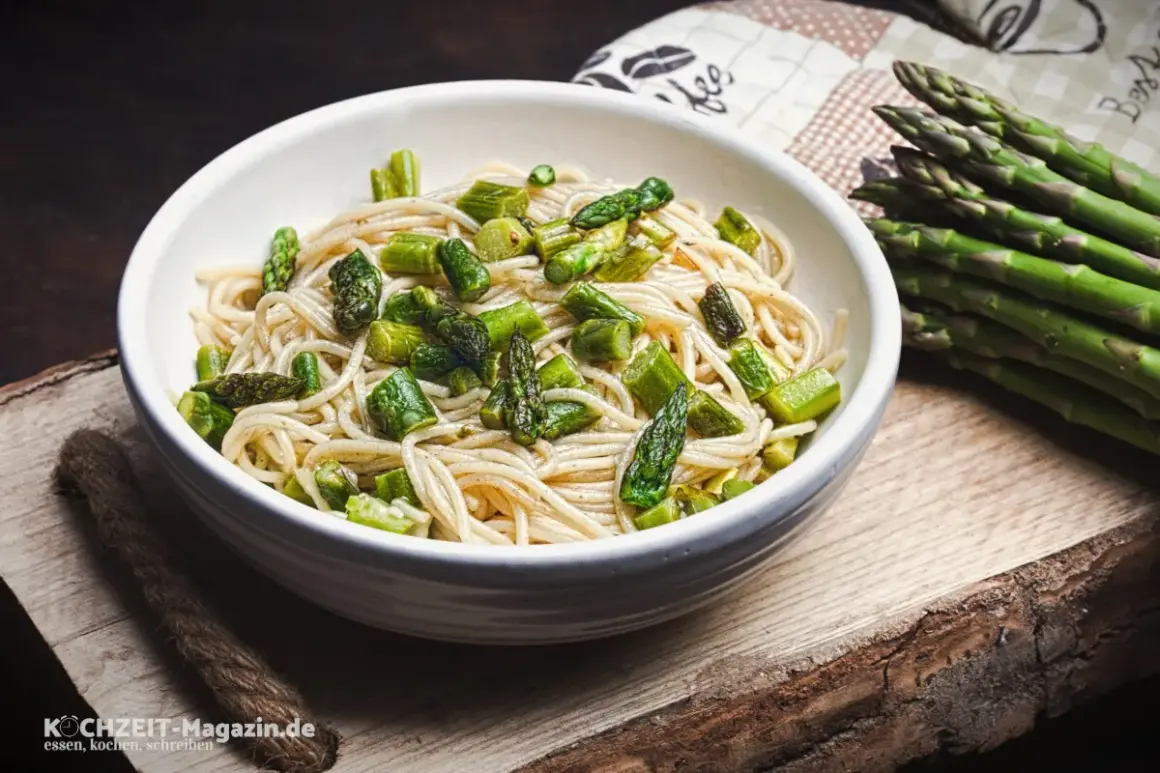 Spargel Pasta: Ein Teller Spaghetti mit frischem, grünem Spargel, daneben ein Bund Spargel.