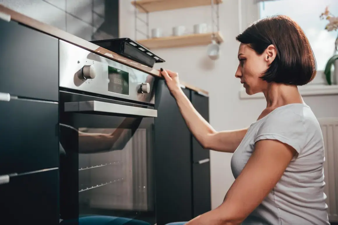 Donna controlla il display del suo forno a gas o elettrico prima di iniziare a cucinare.