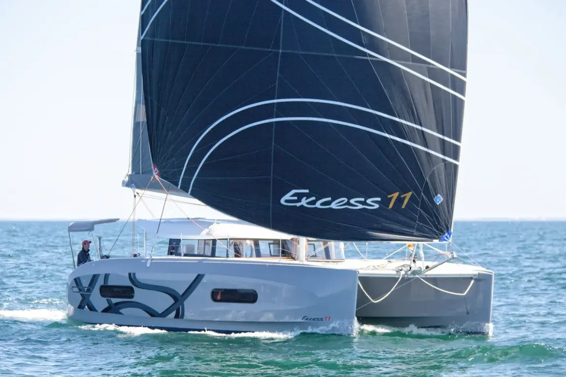 Catamarano Excess 11 con vela nera che naviga in mare aperto.