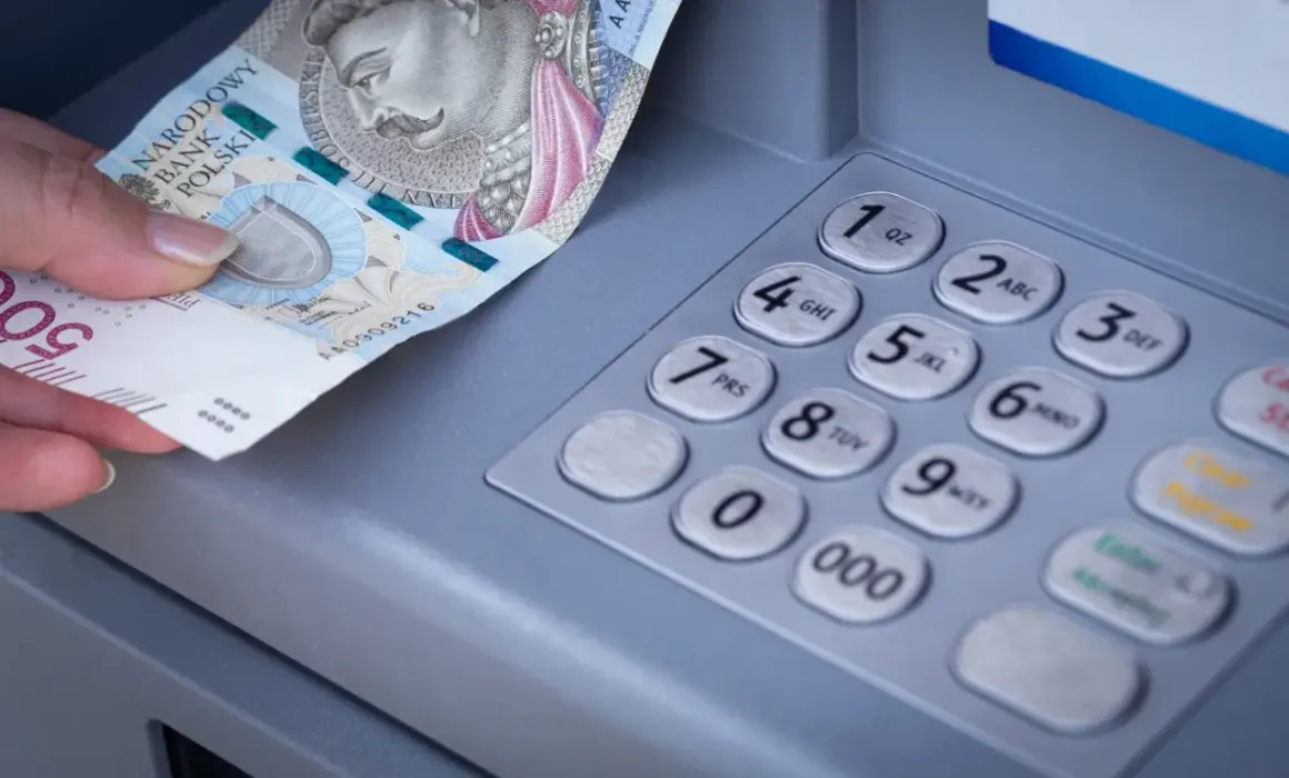 Dłoń wkłada banknot 500 zł do bankomatu. Zastanawiasz się, mbank ile idzie przelew?
