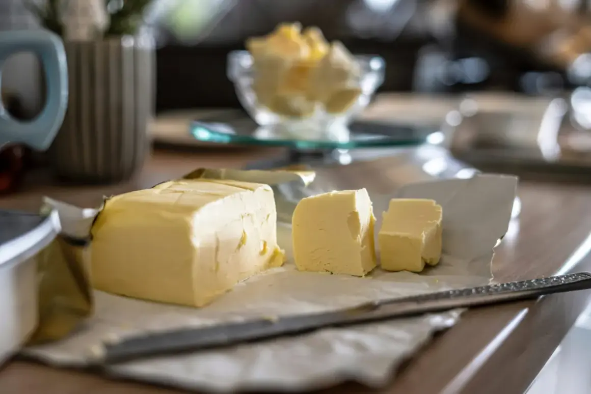 Un bloc de beurre, coupé en morceaux, sur du papier. Le beurre est-il un produit laitier ? Oui, il est fait de crème.