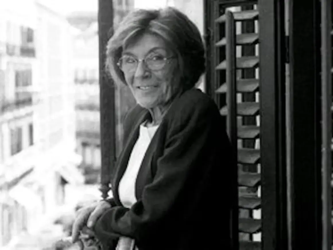 Carmen Rico Godoy, con gafas y chaqueta, mira a la cámara desde un balcón. Parece una escena de "Carmen Rico Godoy abandonada".