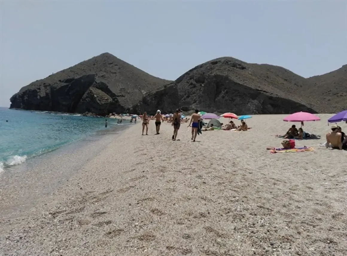 Gente disfrutando del sol y el mar en la playa de los Muertos en Carboneras, con sus icónicas montañas de fondo.