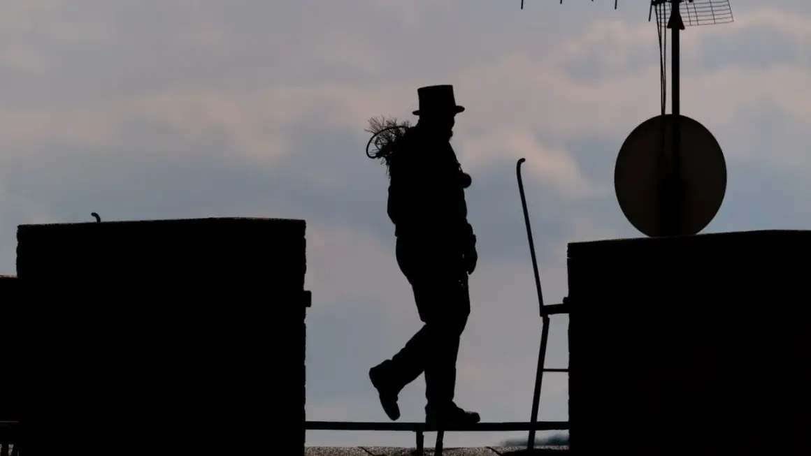 Silhouetten eines Bezirksschornsteinfegers mit Zylinder und Bürste auf dem Dach, der über ein Geländer geht.