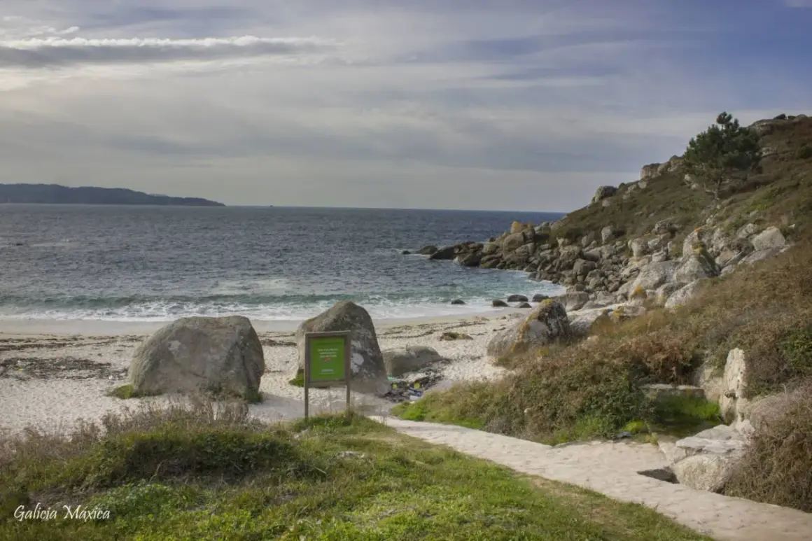 La playa de ancoradouro, con su arena blanca, rocas imponentes y el mar azul, invita a la contemplación. Un sendero de piedra serpentea hacia la costa.