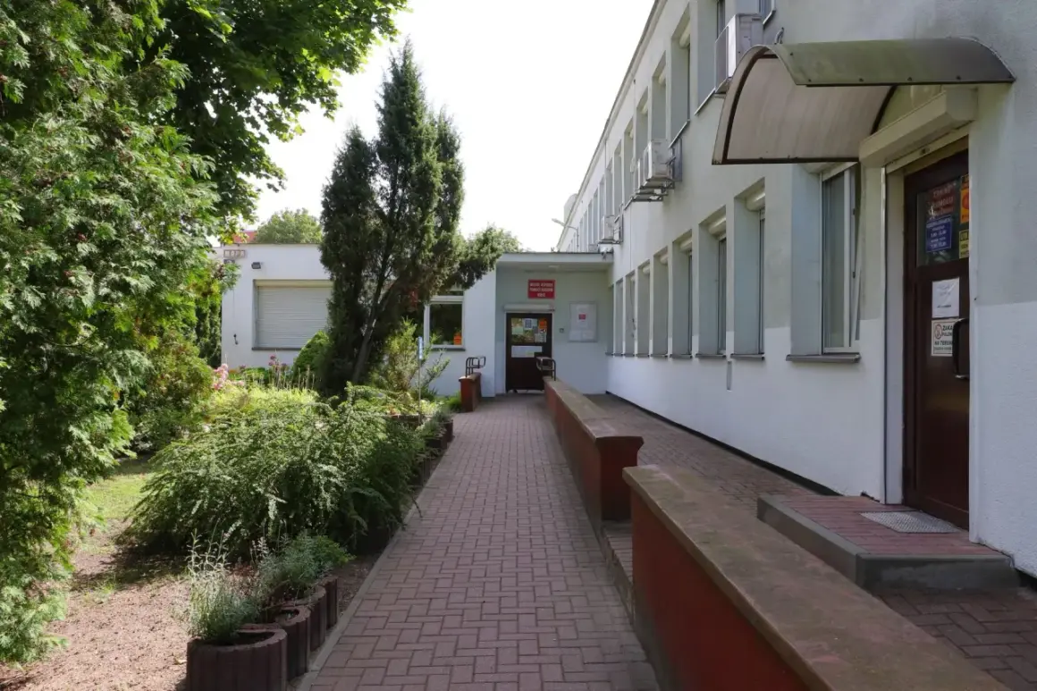 Wejście do Miejskiego Ośrodka Pomocy Rodzinie w Kielcach. Zadbany teren zielony i podjazd dla wózków.