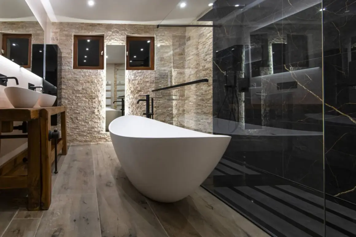 Salle de bain moderne avec baignoire îlot blanche et douche à l'italienne aux murs de marbre noir.