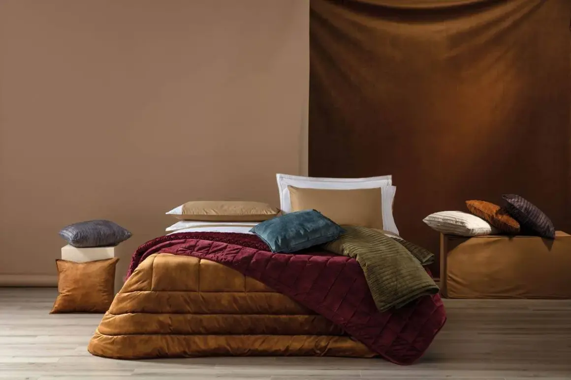 Plaid ai ferri spiegazioni: un letto accogliente con coperte trapuntate color terra e cuscini morbidi, perfetti per un riposo rigenerante.