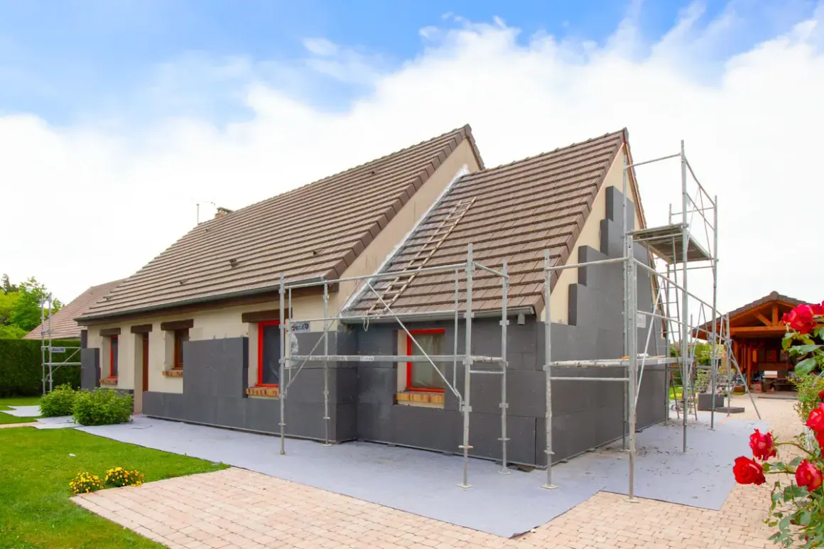 Maison en cours d'isolation par l'extérieur. Les inconvénients sont visibles : échafaudages, accès gêné, et aspect inachevé.